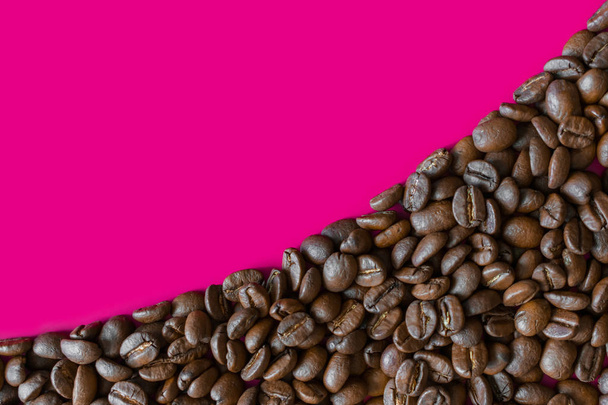 Coffee beans lined with a solid texture on a pink background. Space for text in the upper left - Photo, Image