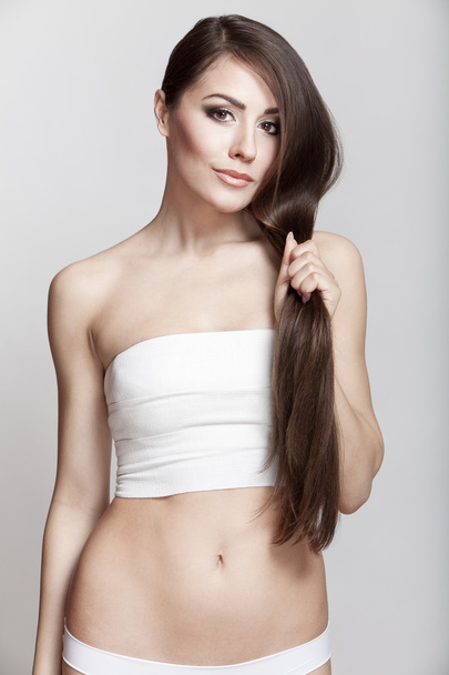 Beautiful young brunette woman holding her hair - Fotoğraf, Görsel