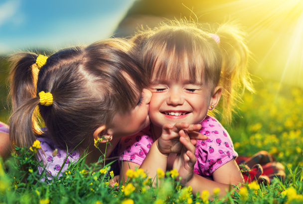幸せな女の子双子の姉妹のキスと夏の屋外環境での笑い - 写真・画像
