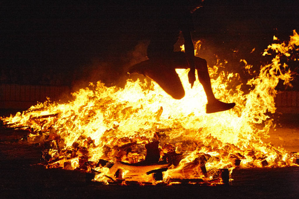 Nyári napforduló ünnepség Spanyolországban. Nő ugrik. Tűz lángjai - Fotó, kép