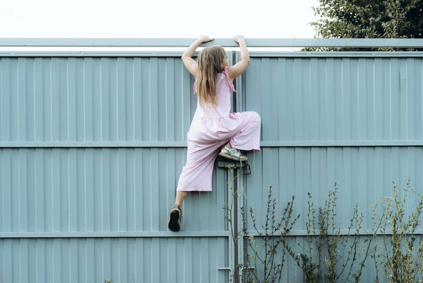 Girl climbing metal fence outdoor - Valokuva, kuva