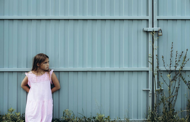 Little serious girl posing near metal gates outdoor - Foto, Imagen