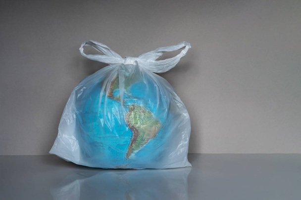 Earth globe in plastic bag on grey background - Zdjęcie, obraz
