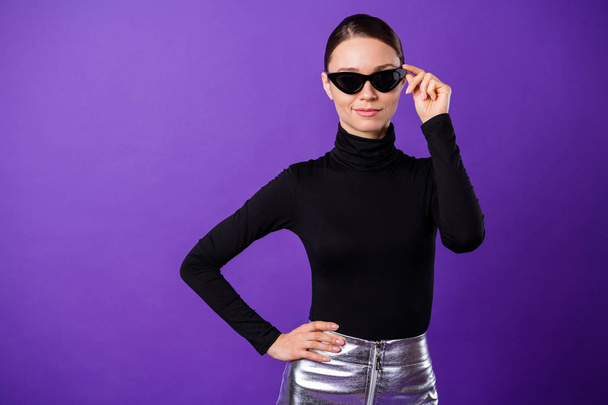 Portrait of charming millennial touching her specs looking putting hands on waist isolated over purple violet background - Foto, immagini
