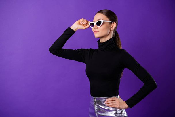 Portrait of concentrated sweet person touching her specs wearing black turtleneck isolated over purple violet background - Photo, Image