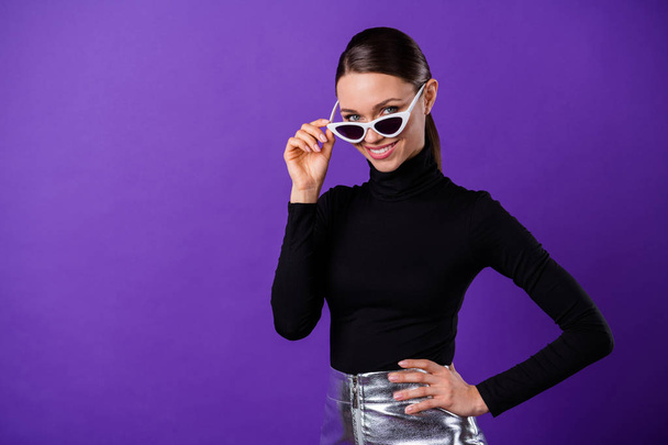 Portrait of lovely person touching her specs with toothy smile looking at camera wearing black turtleneck isolated over purple violet background - Valokuva, kuva