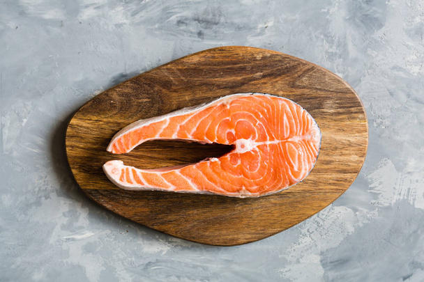 Bife de peixe de salmão cru fresco no fundo de pedra escura. Layout criativo feito de peixe, vista superior, flat lay, mockup, sobrecarga. Conceito de alimentação saudável
 - Foto, Imagem