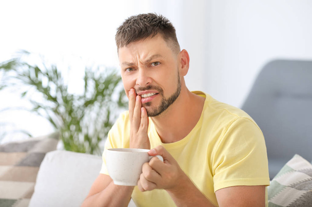 Homme aux dents sensibles et café chaud à la maison
 - Photo, image
