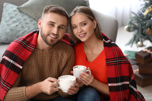 Νεαρό ζευγάρι πίνοντας ζεστή σοκολάτα στο σπίτι - Φωτογραφία, εικόνα