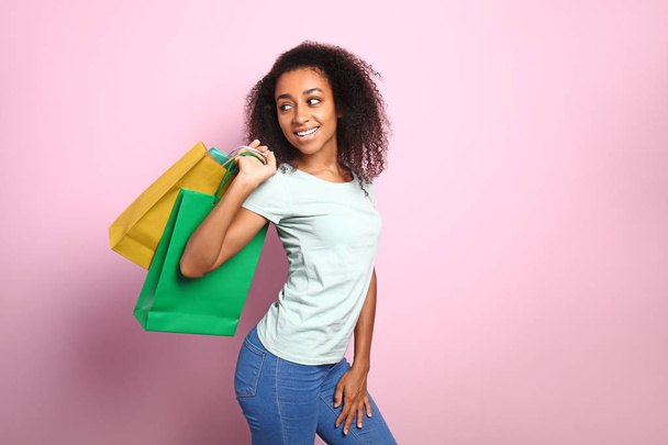 Portrait of happy African-American woman with shopping bags on color background - Photo, Image
