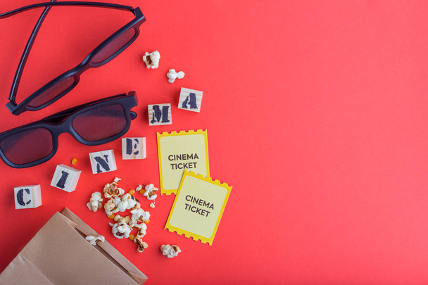 craft bag with popcorn 3d cinema glasses tickets wooden cubes with text on red background creative flatlay - Foto, imagen