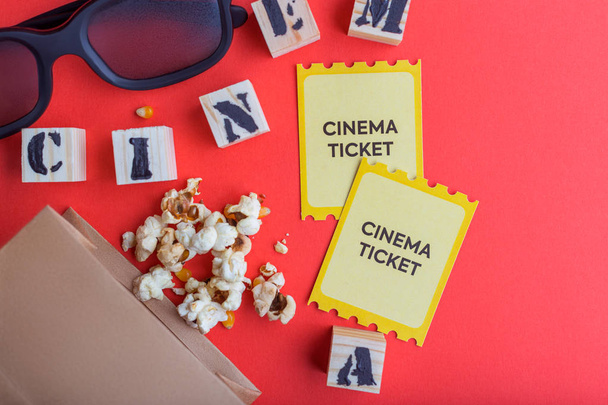 craft bag with popcorn 3d cinema glasses tickets wooden cubes with text on red background creative flatlay - Foto, imagen