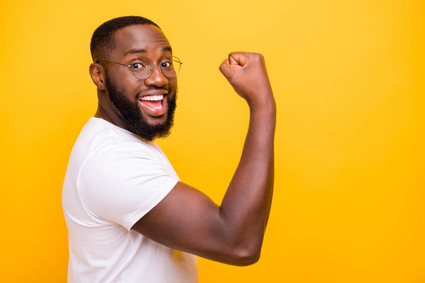 Dark skin guy celebrating lottery winning raising fist up wear casual outfit isolated yellow background - Foto, Bild