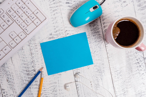 白い木製の床、コンピュータのキーボードとマウスの上に正方形の長方形の空の紙幣。リマインダーの周りにコーヒーと鉛筆のマグカップ。事務用品、空白. - 写真・画像