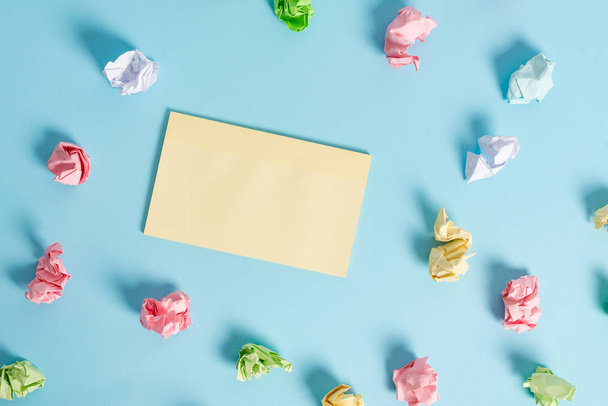 Rectangle square shaped colored paper in a light blue background. Colorful crumpled note spread around the table. Reminder in a blank space. Office supplies in a desk. - Photo, Image