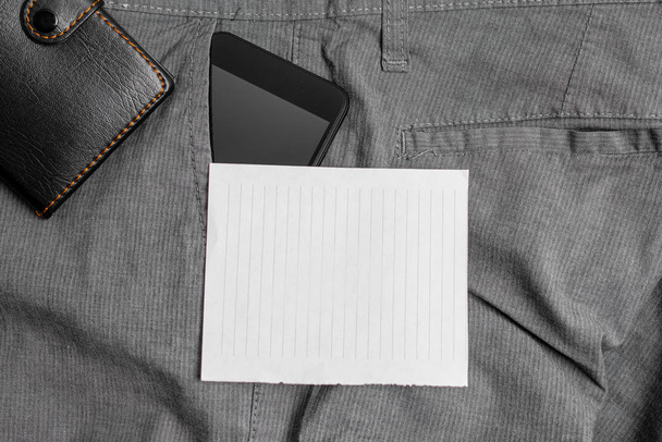 Dispositivo Smartphone no bolso frontal das calças com uma carteira e papel branco. gadget moderno é colocado dentro de calças homem perto da folha de notação mais bolsa
 - Foto, Imagem