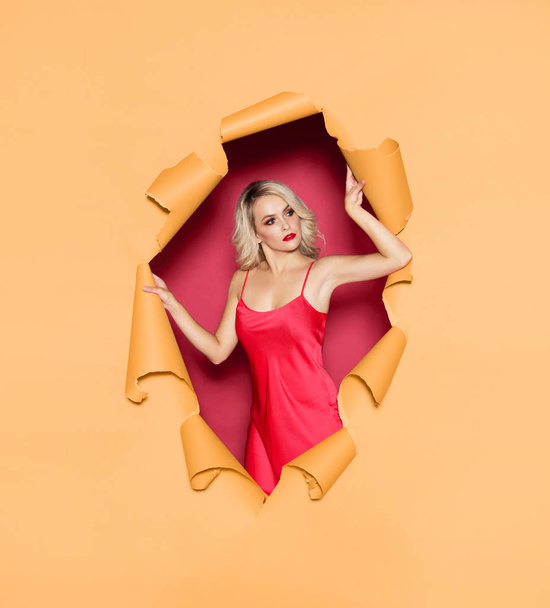 Young and beautiful blond woman in a red dress over yellow torn paper background. Fall, autumn sales, shopping and discount concept. - Foto, immagini
