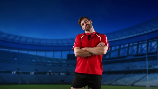 Animacja kaukaski mężczyzna gracz rugby stojący z ramionami skrzyżowane i patrząc na aparat fotograficzny z stadionu w tle - Materiał filmowy, wideo