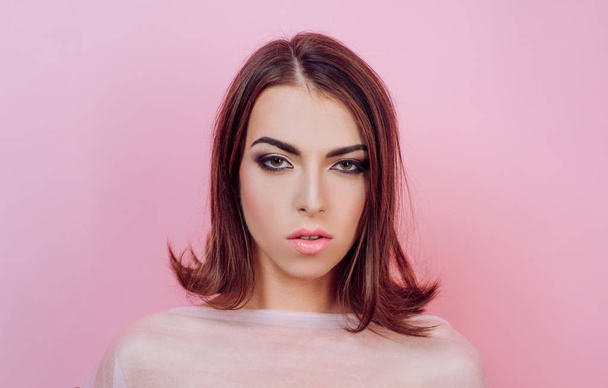 Beauty woman face on pink background. Hairstyle styling. Fashion, beauty, cosmetics. Perfect makeup, smooth skin. Advertisement, magazine. - Foto, Imagem