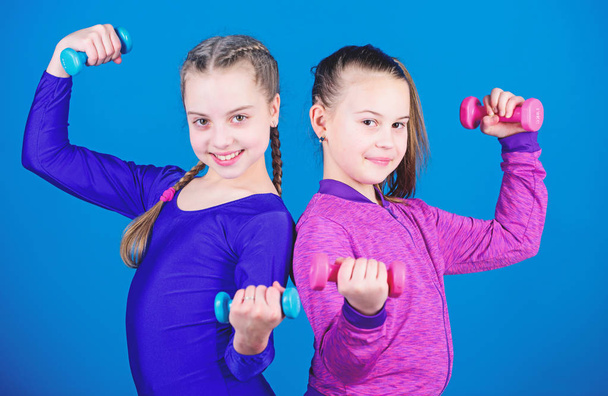 Fitness-Diät für Energie Gesundheit. Trizepstraining für kleine Mädchen mit einer Kurzhantel. Sporterfolg. Gewichtheben für Muskeln. glücklicher Kindersportler mit Langhantel. Trizeps-Übung. Trizepsworkout - Foto, Bild