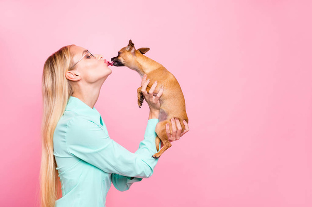 Profile side photo of lovely person having eyeglasses eyewear hold doggy liking her wearing mint color shirt isolated over pink background - Фото, зображення