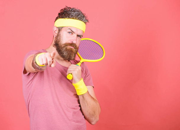 Concentrated on tennis court. Athlete hipster hold tennis racket in hand red background. Tennis sport and entertainment. Man bearded hipster wear sport outfit. Tennis player beginner retro fashion - Photo, Image
