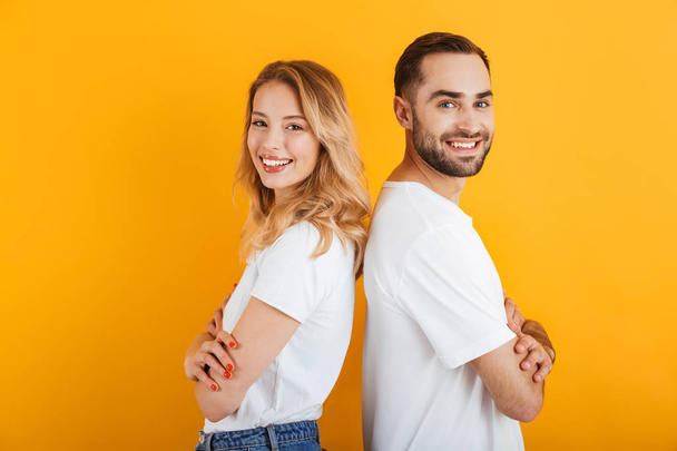 Image of caucasian people man and woman in basic t-shirts smiling while standing back to back - Foto, afbeelding