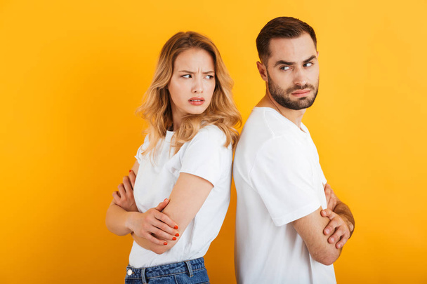Image of upset couple man and woman in basic t-shirts frowning while standing back to back during fight - Fotoğraf, Görsel