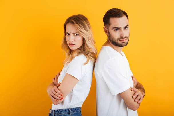 Image of confused couple man and woman in basic t-shirts frowning while standing back to back during fight - Fotografie, Obrázek