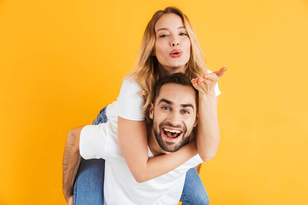 Image of joyful couple laughing and having fun while handsome guy piggybacking pretty woman - Photo, Image