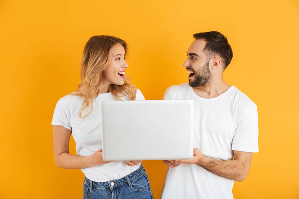 Image of pretty couple man and woman rejoicing while holding laptop together - Foto, Imagen