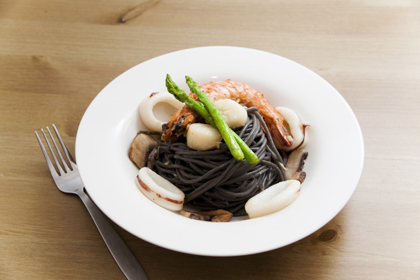 Black spaghetti with seafood on wooden table (squid ink pasta) - Foto, Imagem