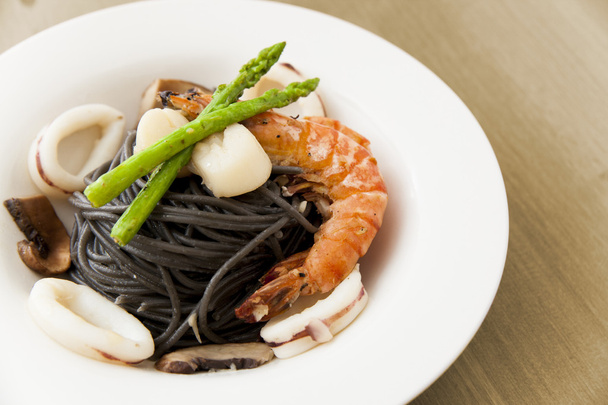 Black spaghetti with seafood on wooden table (squid ink pasta) - Fotografie, Obrázek