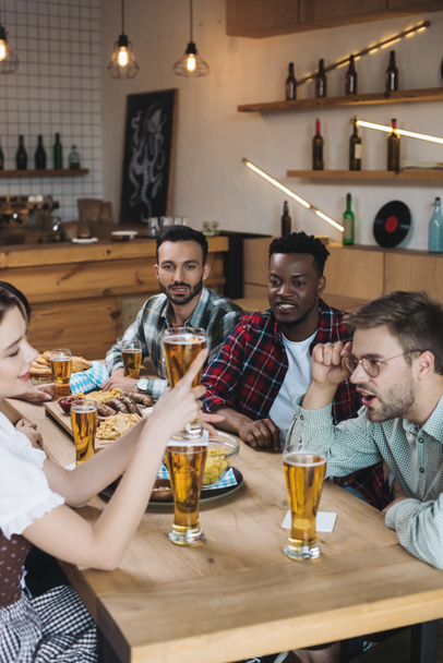 cheerful multicultural friends celebrating octoberfest together in pub - Photo, Image