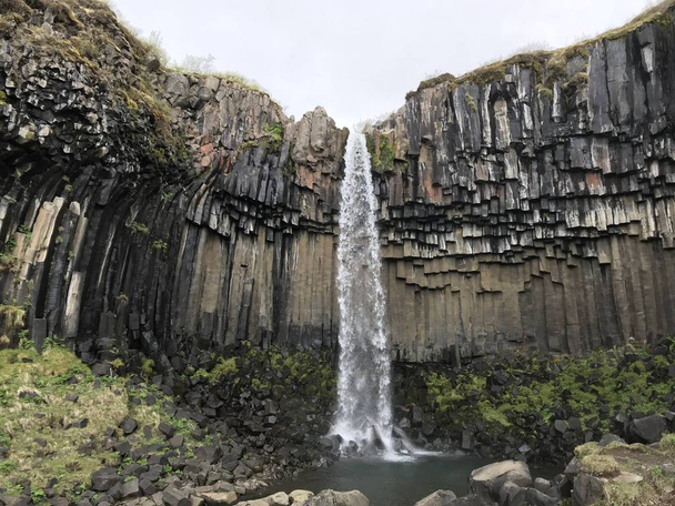 20-метровий водоспад вниз по центру драматичної 3D стіни шестикутних базальтових колон
 - Фото, зображення