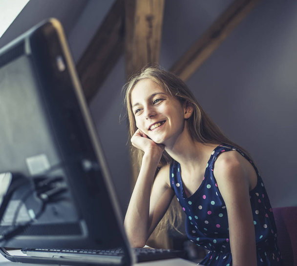 ευτυχισμένο έφηβο κορίτσι κάθεται στον υπολογιστή - Φωτογραφία, εικόνα
