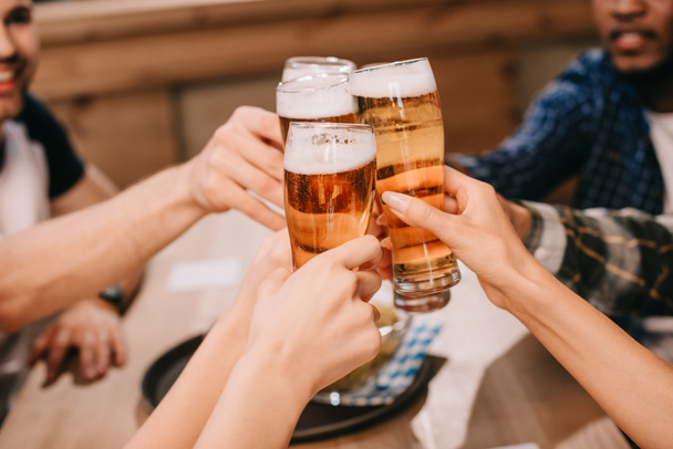 vista recortada de amigos multiculturales tintineo vasos con cerveza lager en el pub
 - Foto, imagen