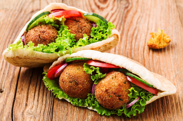 Falafel and fresh vegetables in pita bread on wooden table - Photo, Image