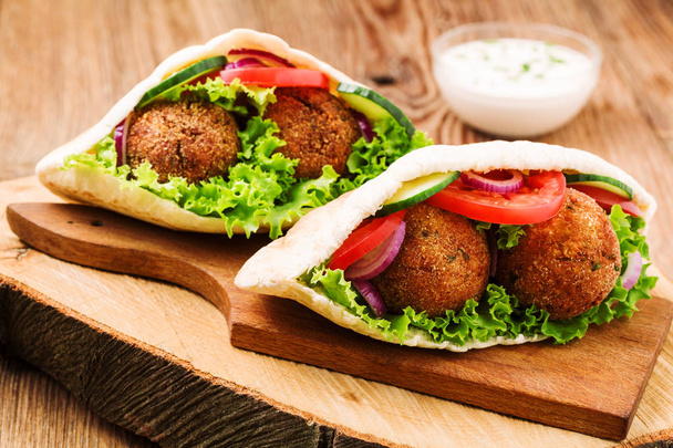 Falafel and fresh vegetables in pita bread on wooden table - Foto, imagen