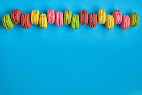 Colored macaron or macaroon, sweet meringue-based confection on blue background. Close-up, copy space. - Foto, immagini