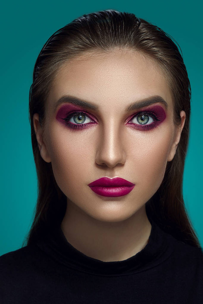 Close-up glamour portrait of a beautiful model with bright make-up posing over a gray background. - 写真・画像