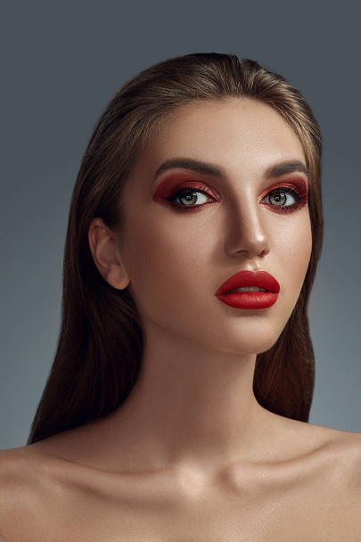 Glamour-Porträt in Großaufnahme eines schönen halbnackten Models mit hellem Make-up, das vor grauem Hintergrund posiert. - Foto, Bild