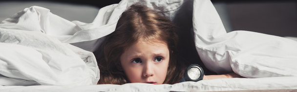 ijedt gyermek bujkál alatt takaró zseblámpával izolált fekete - Fotó, kép