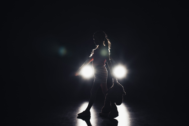 lapsi kävelee pimeydessä valaistu ajovalot mustalla taustalla
 - Valokuva, kuva