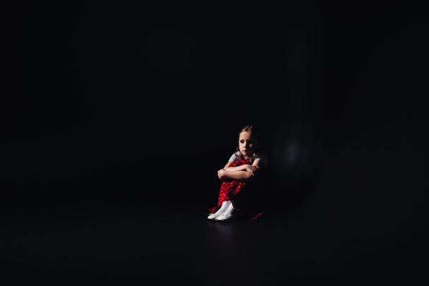peloissaan, yksinäinen lapsi istuu lattialla mustalla taustalla kopiotilaa
 - Valokuva, kuva