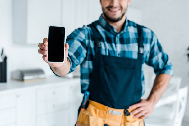 περικομμένη όψη του ευτυχισμένο μούσι πολυτεχνίτης κρατώντας smartphone με κενή οθόνη  - Φωτογραφία, εικόνα
