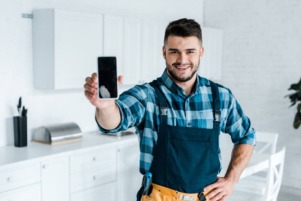 selektivní zaměření šťastného vousatého Handymana, který drží smartphone s prázdnou obrazovkou  - Fotografie, Obrázek