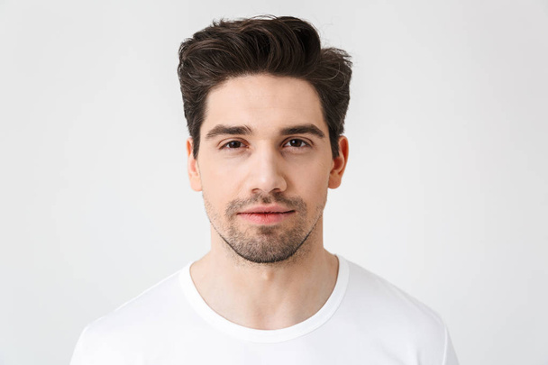 Serious concentrated young man posing isolated over white wall background. - 写真・画像