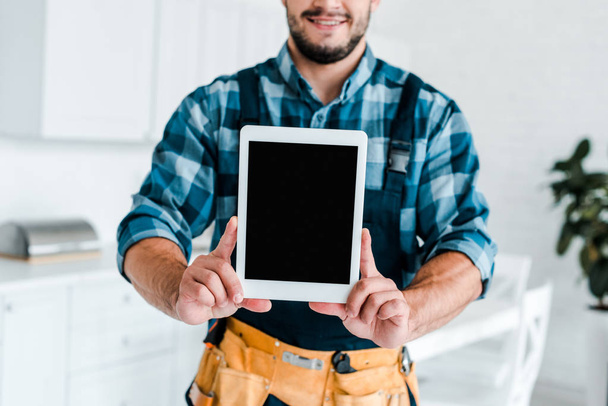 cropped view of happy handyman holding digital tablet with blank screen  - 写真・画像