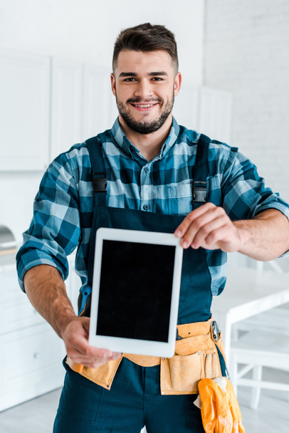 selective focus of happy handyman holding digital tablet with blank screen  - 写真・画像